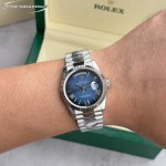 Sunday Calendar series women's watch with diamond-set gradient blue dial, diamond-set bezel, 36mm case, and silver President-style bracelet.